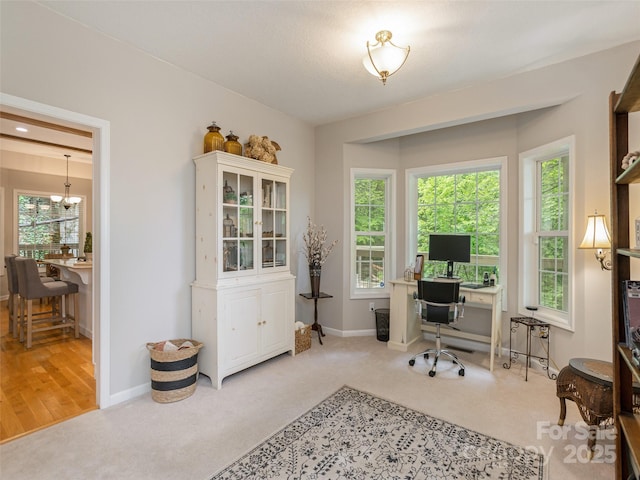 carpeted home office with baseboards and a chandelier
