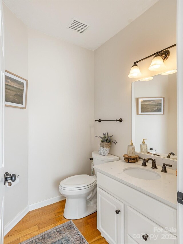 bathroom with wood finished floors, toilet, vanity, and baseboards