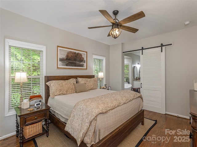 bedroom featuring a barn door, multiple windows, and wood finished floors