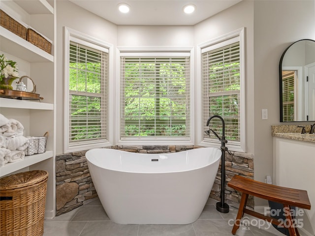 bathroom with a soaking tub, tile patterned flooring, and vanity