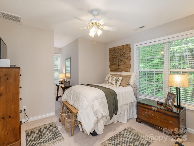 bedroom featuring multiple windows, baseboards, light colored carpet, and a ceiling fan