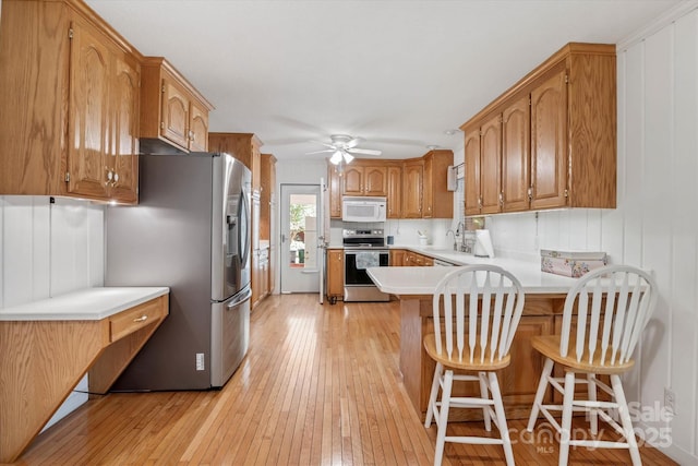6003 Woodbridge Rd, Charlotte, NC 28227 - kitchen featuring stainless steel appliances, a peninsula, light wood-style flooring, a ceiling fan, and light countertops