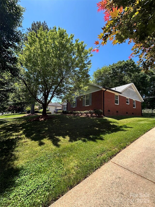 view of property exterior featuring crawl space, a lawn, and brick siding