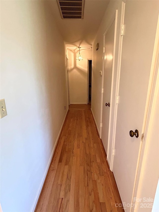 hall with light wood-style floors and baseboards