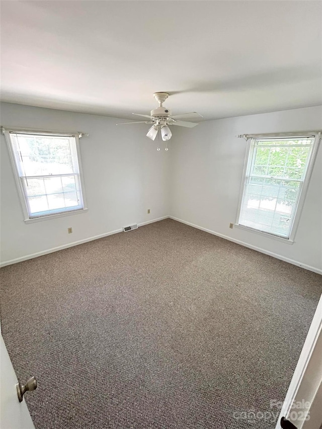 carpeted spare room featuring plenty of natural light, baseboards, and a ceiling fan