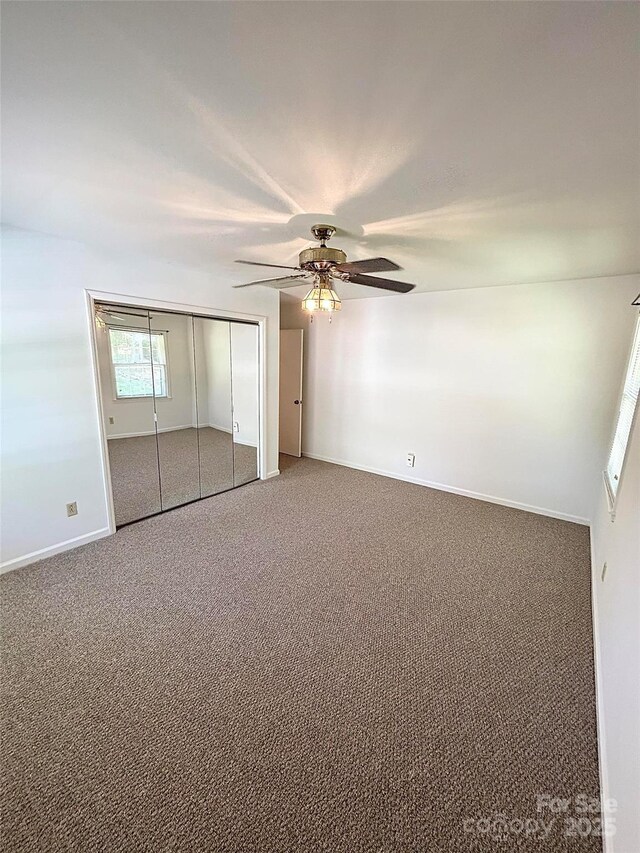 unfurnished bedroom with carpet flooring, baseboards, a ceiling fan, and a closet