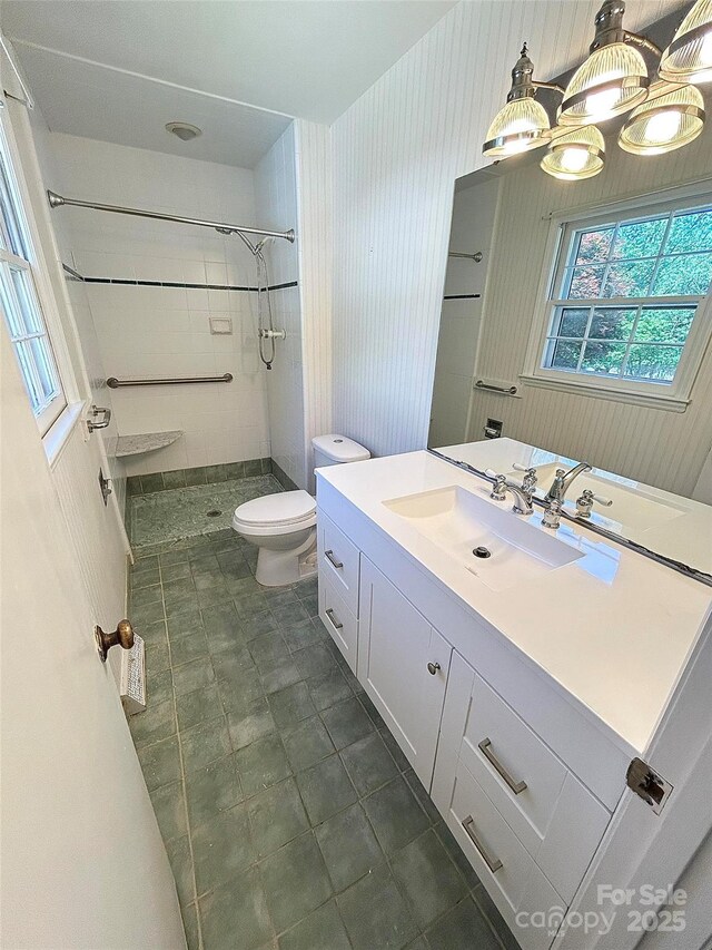 bathroom featuring toilet, tiled shower, vanity, and tile patterned flooring