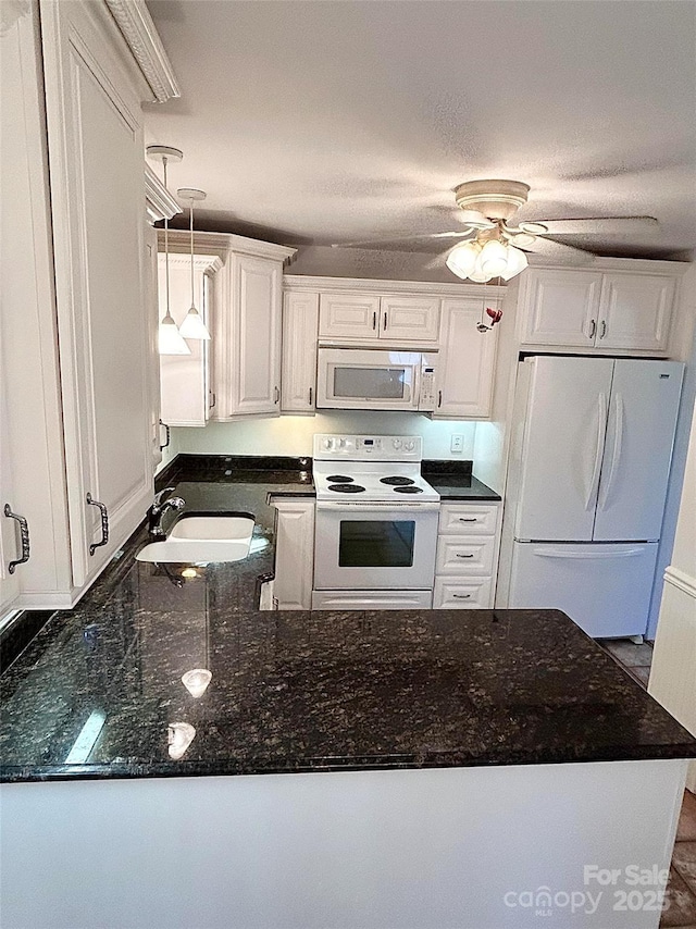 kitchen featuring white appliances, a sink, white cabinetry, a peninsula, and decorative light fixtures