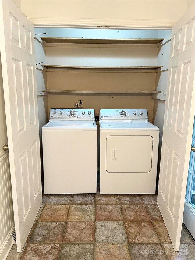 clothes washing area featuring washing machine and clothes dryer and stone finish floors