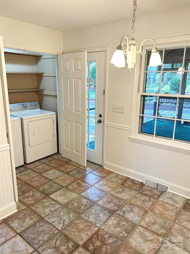 foyer featuring a chandelier, washer and dryer, stone finish flooring, and wainscoting