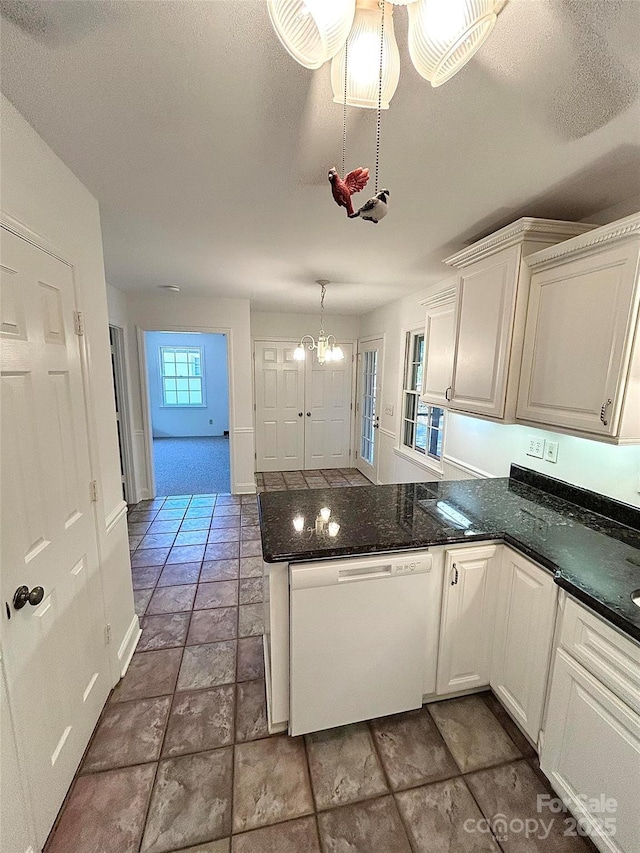kitchen featuring dishwasher, a peninsula, white cabinetry, stone finish floors, and a chandelier