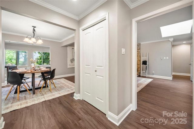 dining room with dark wood-style flooring, baseboards, a chandelier, a skylight, and ornamental molding