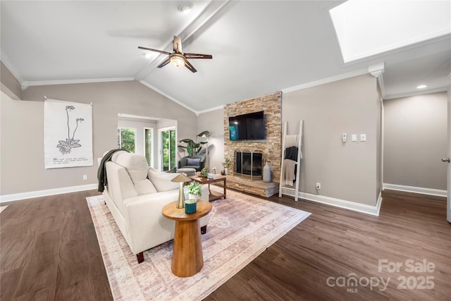 living area featuring dark wood-style floors, a ceiling fan, a fireplace, baseboards, and crown molding