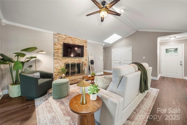 living area featuring dark wood-style floors, ceiling fan, baseboards, a fireplace, and crown molding