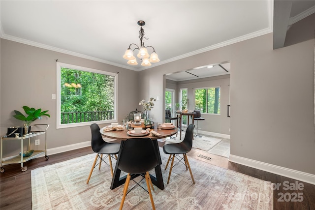dining room featuring baseboards, ornamental molding, a chandelier, and wood finished floors