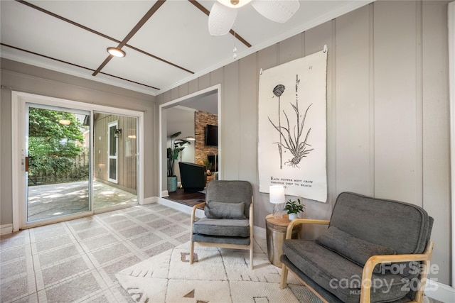 living area with ceiling fan, crown molding, baseboards, and light carpet