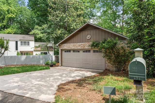 view of front of home featuring concrete driveway, stone siding, fence, and an attached garage
