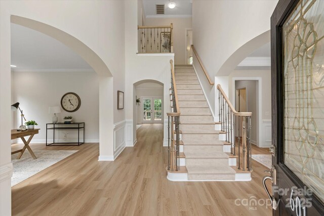 601 Carver Pond Ln, Waxhaw, NC 28173 - foyer entrance featuring arched walkways, ornamental molding, light wood-type flooring, a high ceiling, and stairs