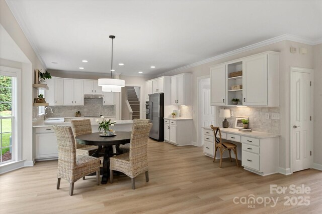 601 Carver Pond Ln, Waxhaw, NC 28173 - dining space with light wood-style floors, crown molding, recessed lighting, and stairway