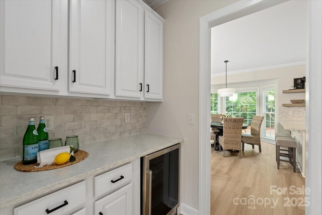 601 Carver Pond Ln, Waxhaw, NC 28173 - bar area with wine cooler, ornamental molding, decorative backsplash, and light wood-style floors