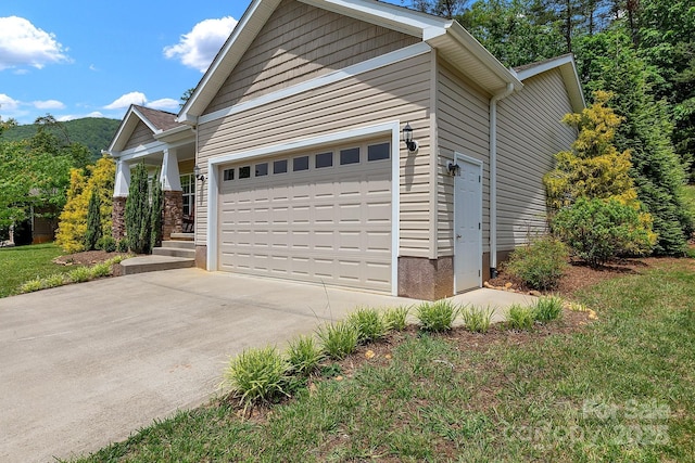 view of side of home with concrete driveway and an attached garage