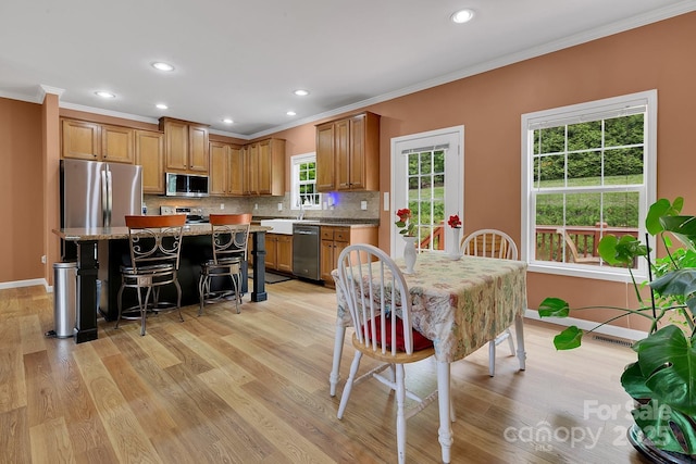 kitchen with stainless steel appliances, crown molding, a kitchen island, light wood-style floors, and tasteful backsplash
