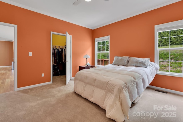 bedroom with ornamental molding, light colored carpet, baseboards, a spacious closet, and a closet