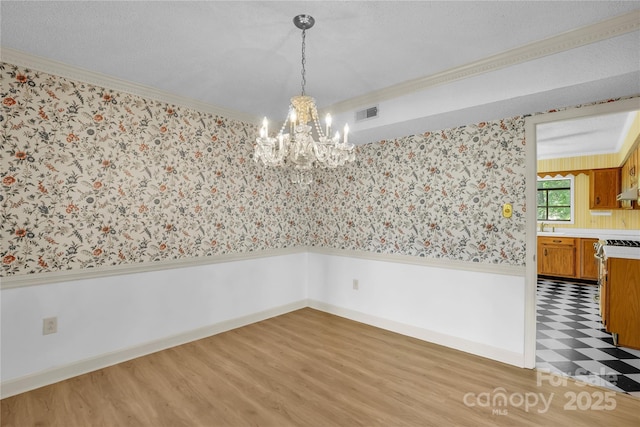 4738 Truscott Rd, Charlotte, NC 28226 - unfurnished dining area with wainscoting, ornamental molding, wallpapered walls, a chandelier, and light wood-style floors