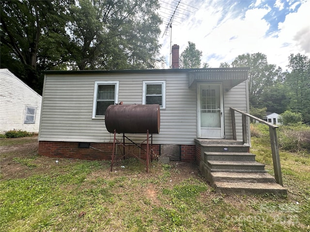 rear view of property with heating fuel, crawl space, and a chimney