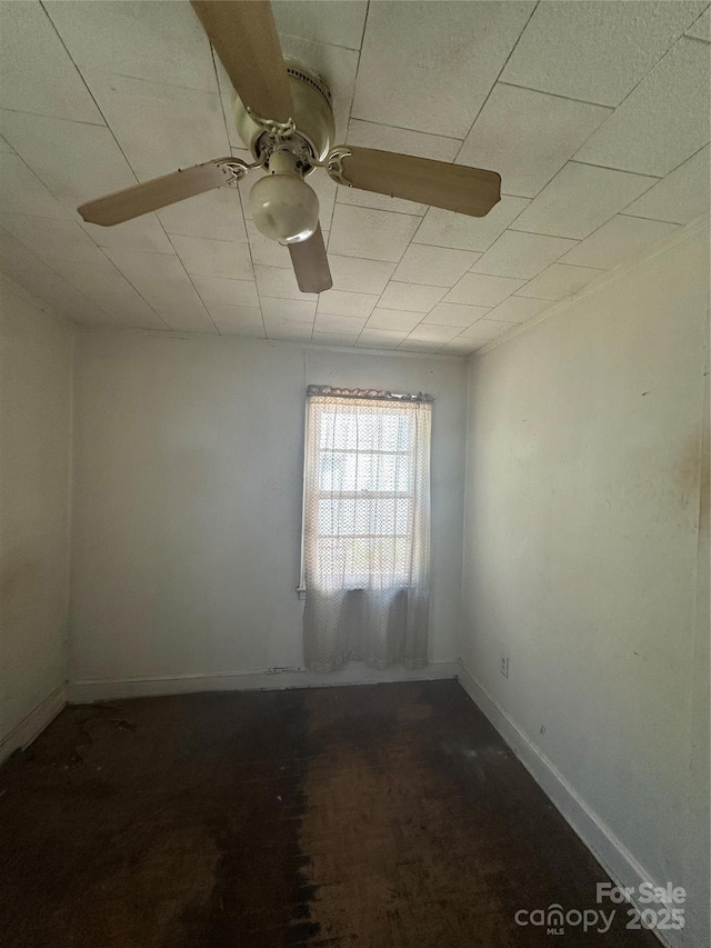 unfurnished room featuring a ceiling fan and baseboards