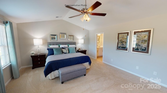 bedroom featuring lofted ceiling, light colored carpet, baseboards, and ensuite bath