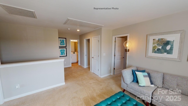 living area featuring attic access, light colored carpet, and baseboards