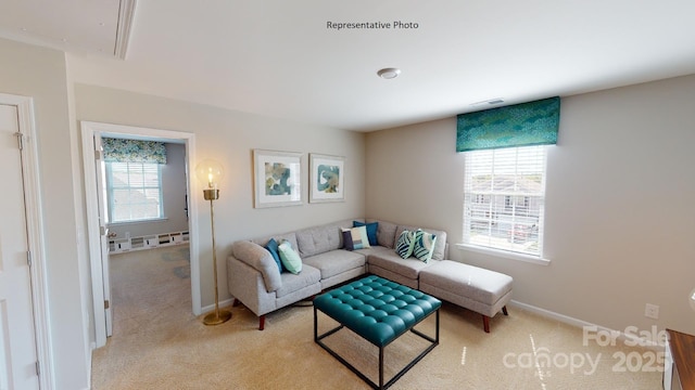 living room featuring attic access, light carpet, and baseboards
