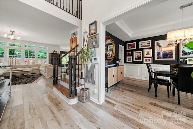 staircase featuring a chandelier, wood finished floors, a decorative wall, and a wainscoted wall
