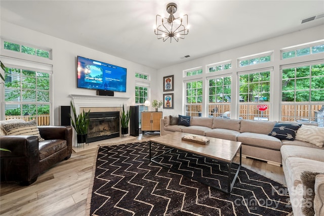 living room featuring hardwood / wood-style floors, a glass covered fireplace, a chandelier, and healthy amount of natural light