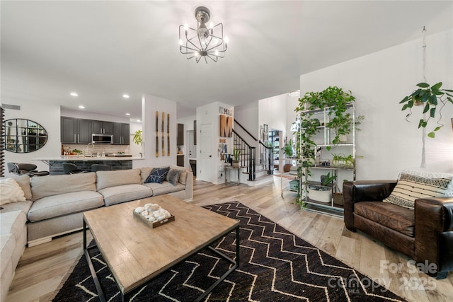 living area featuring stairway, light wood-style flooring, a chandelier, and recessed lighting