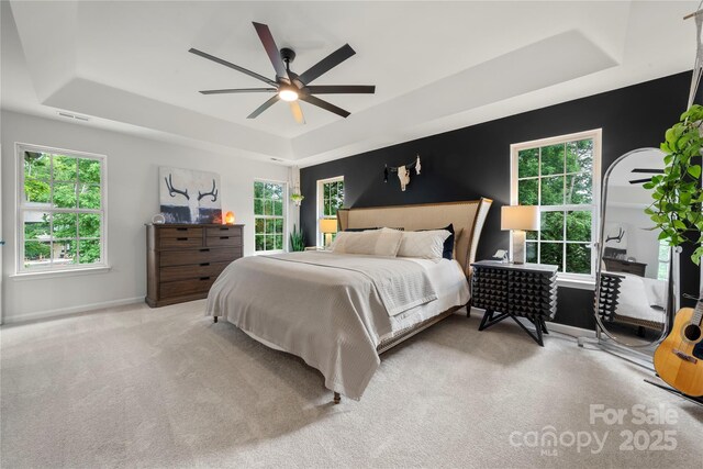 carpeted bedroom with a tray ceiling, baseboards, and a ceiling fan