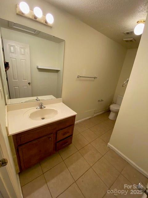 5309 Lewis Rd, Gastonia, NC 28052 - half bathroom with tile patterned flooring, toilet, a textured ceiling, vanity, and baseboards