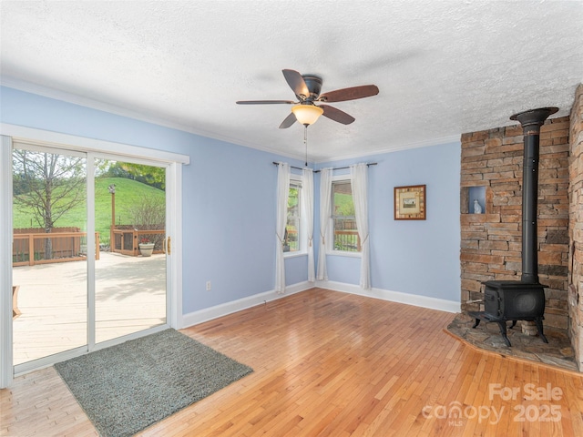 10 Gardening Frog Trl, Waynesville, NC 28785 - unfurnished living room with a wood stove, light wood-style flooring, baseboards, ceiling fan, and a textured ceiling