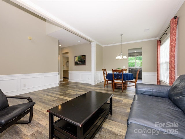 3224 Dunbar Ln, Fort Mill, SC 29707 - living room featuring wood finished floors, a chandelier, wainscoting, ornate columns, and ornamental molding