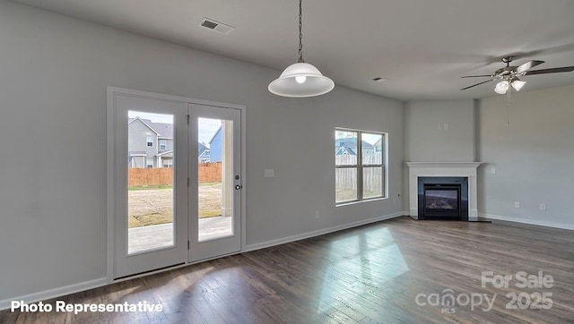 unfurnished living room featuring wood finished floors, baseboards, a glass covered fireplace, and a ceiling fan