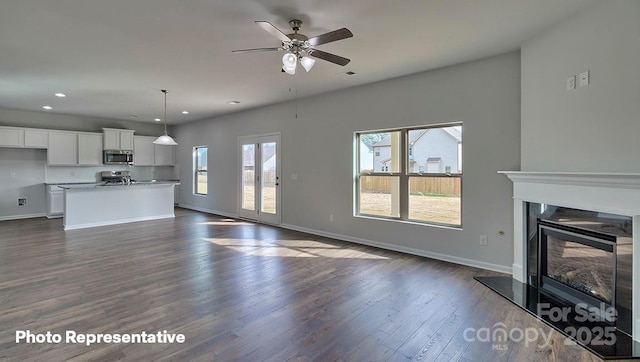 unfurnished living room featuring recessed lighting, baseboards, dark wood-style floors, a ceiling fan, and a glass covered fireplace