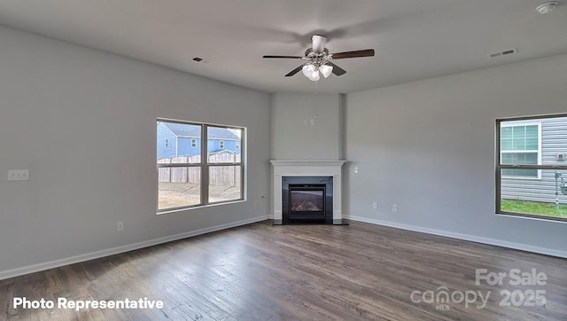 unfurnished living room with wood finished floors, a ceiling fan, baseboards, and a glass covered fireplace