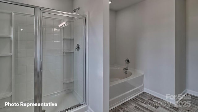full bathroom with a shower stall, a bath, baseboards, and wood finished floors