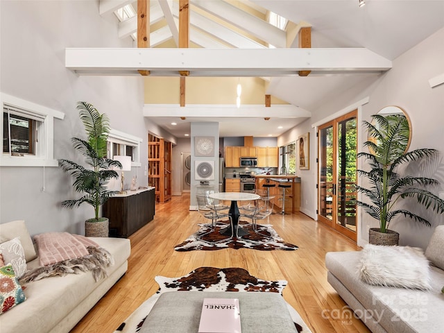 11 Kenilworth Rd, Asheville, NC 28803 - living room featuring stacked washer and clothes dryer, beamed ceiling, high vaulted ceiling, a skylight, and light wood-type flooring