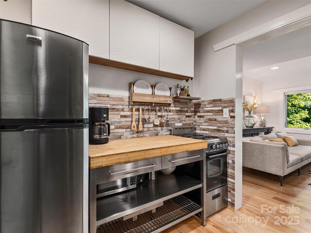 11 Kenilworth Rd, Asheville, NC 28803 - kitchen with stainless steel appliances, butcher block counters, open shelves, decorative backsplash, and light wood-style floors