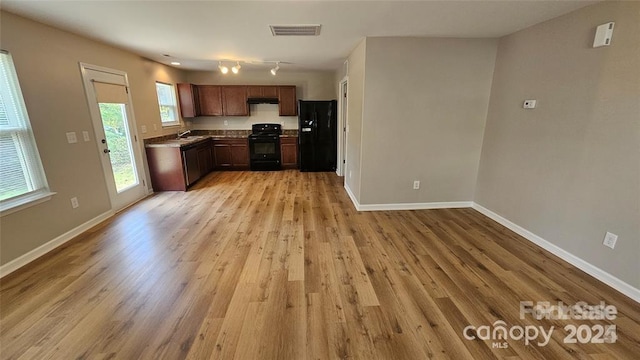 5823 Natick Dr, Charlotte, NC 28214 - kitchen featuring black appliances, light wood-style flooring, baseboards, under cabinet range hood, and a sink