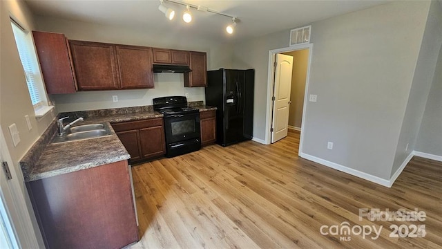5823 Natick Dr, Charlotte, NC 28214 - kitchen featuring black appliances, a sink, under cabinet range hood, dark countertops, and light wood-type flooring