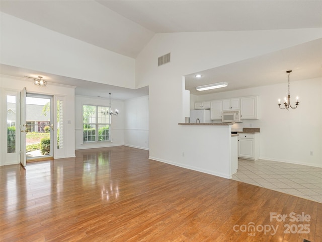 14 Stonehollow Rd, Fletcher, NC 28732 - unfurnished living room with a chandelier, light wood-style floors, baseboards, and high vaulted ceiling