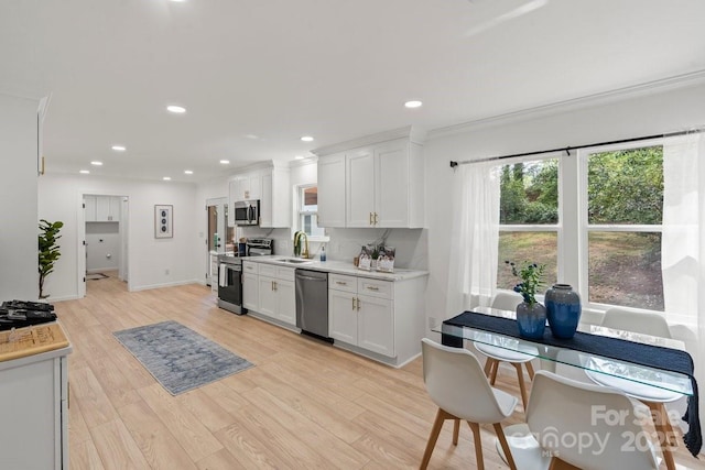 5910 Grosner Pl, Charlotte, NC 28211 - kitchen featuring appliances with stainless steel finishes, white cabinets, light countertops, light wood-style floors, and plenty of natural light